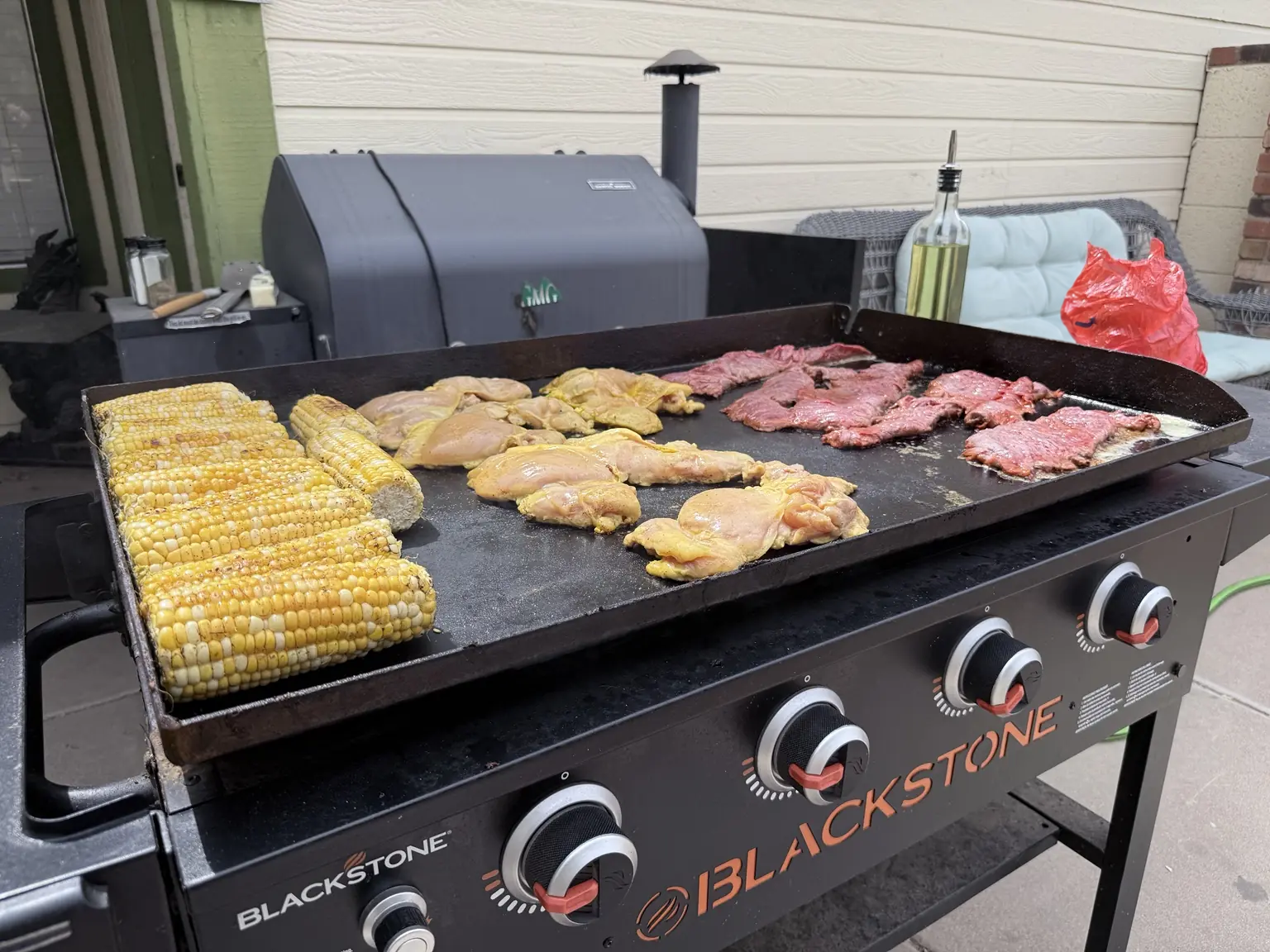 Corn, carne, and seasoned chicken cooking on a Blackstone for tacos